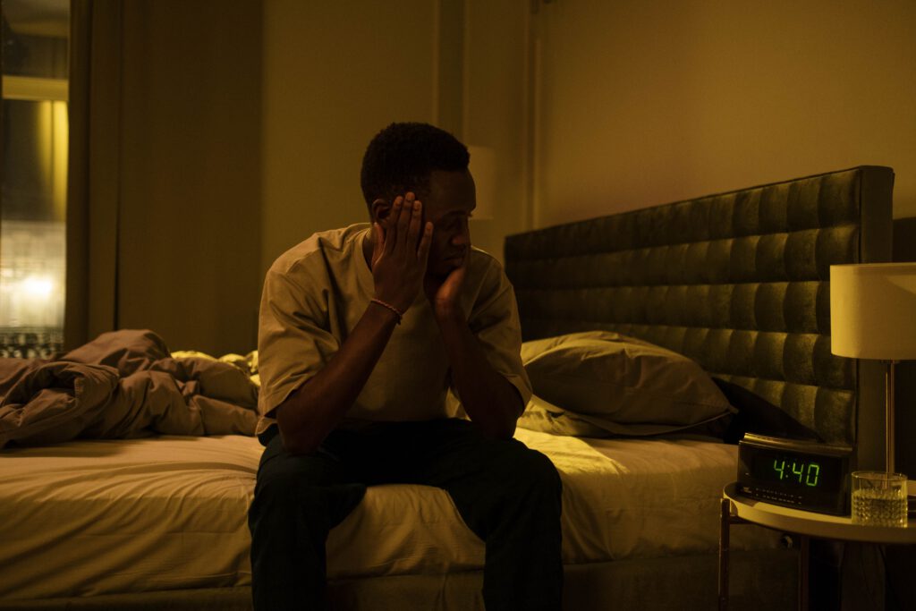 Man awake beside his bed during the night with a digital clock showing 4:40