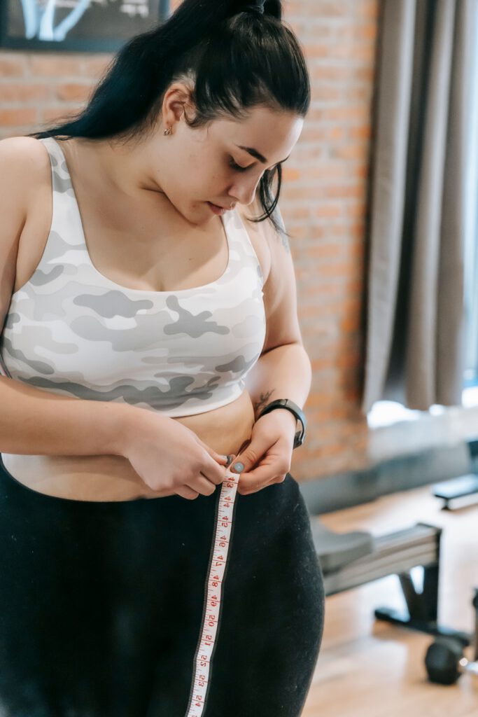 Person measuring their waist representing a weight transformation goal